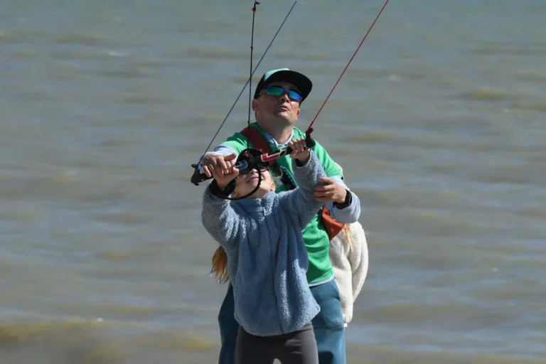 Instructor helping a child hold the control bar of a trainer kite