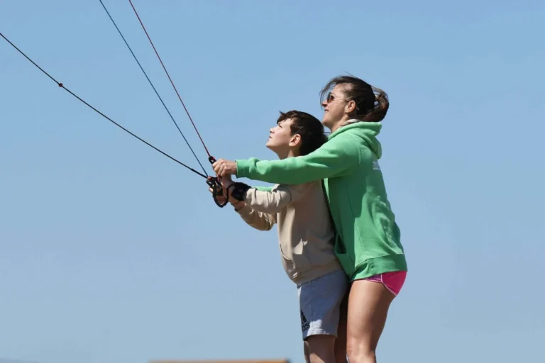 Coach guiding a boy as he flies a trainer kite at Kids Day